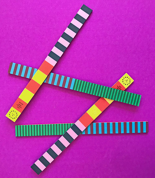 colorful rulers laying on a bright pink background