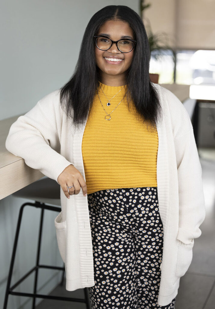 Cierra Fountain, graphic designer, stands in a bright open coworking space
