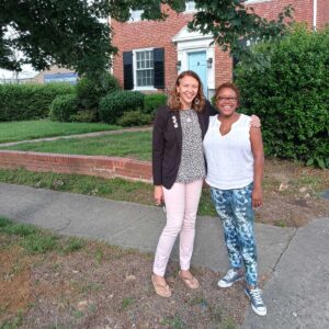 Two women standing next to each other posing for picture.